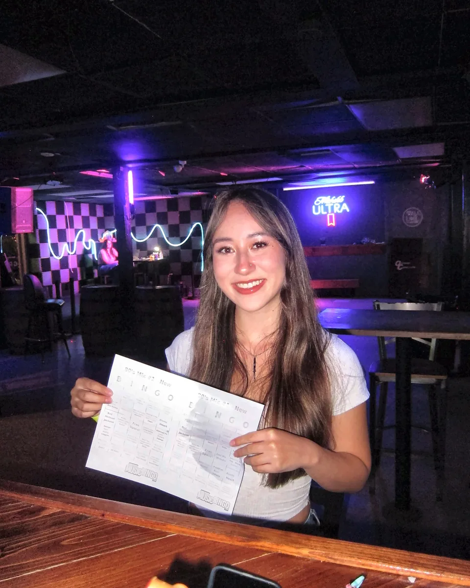 Guest holding a music bingo sheet inside Greene Street Pool Tavern.